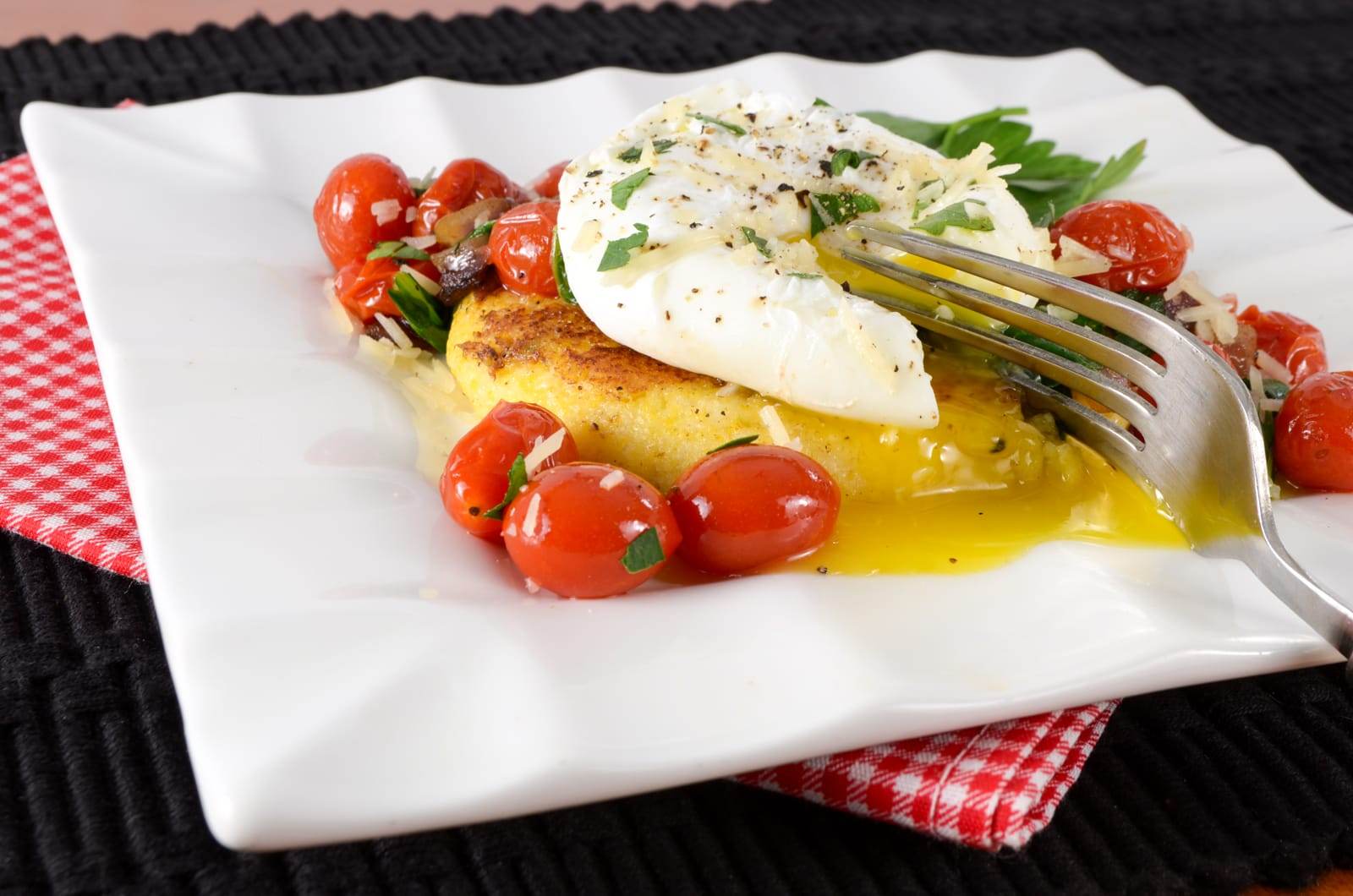 Polenta Cake Topped with Sautéed Tomatoes, Spinach, and a Poached Egg